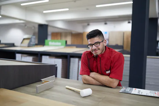 LaminatDEPOT Auszubildender in der Filiale mit Laminat und Verlegehammer