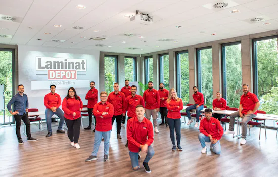Gruppenfoto LaminatDEPOT Auszubildende mit Leinwand und LaminatDEPOT Logo