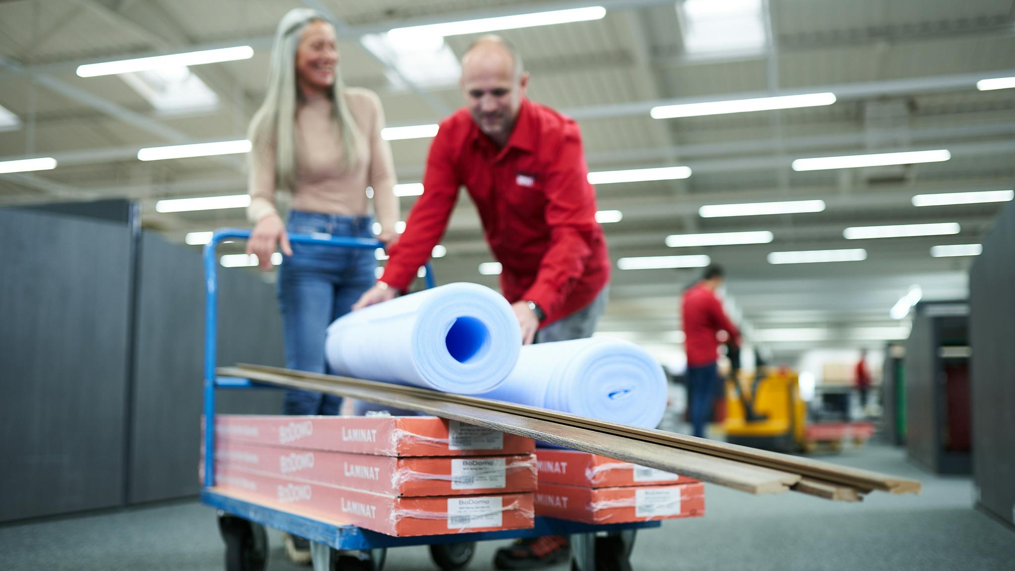 Mitarbeiter vom LaminatDEPOT und Kundin mit Einkaufswagen